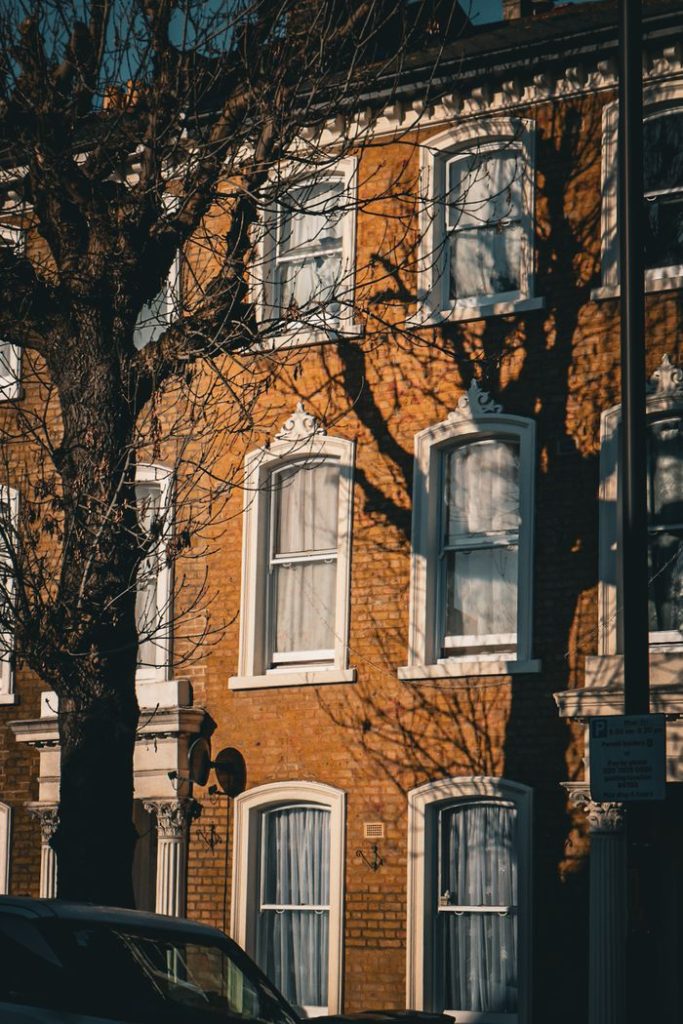 Cozy brick townhouse facade with classic sash windows in urban setting.